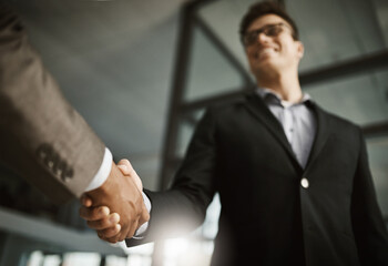 Below of two business peoples handshake during a meeting in an office. Colleagues finalize a successful promotion, deal and merger. Coworkers greet while collaborating and negotiating in interview