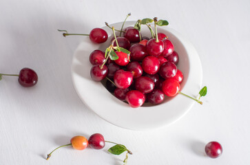 white cup with ripe red cherries on a table,summer harvest of fruits and berries
