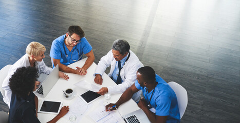 Doctor, nurse and healthcare professional team or group sitting in the boardroom, talking about medicine and discussing treatment during a meeting. Planning and brainstorming a health cure from above