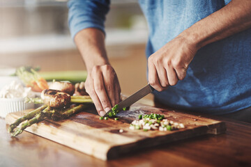 Closeup of man cooking in kitchen, preparing food with fresh vegetables. Homemade lunch by...