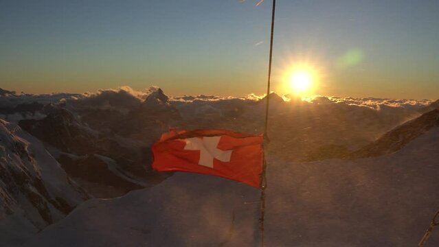 Waving flag of Switzerland with Matterhorn summit during sunset