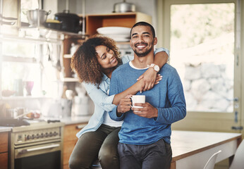 Happy, hugging and smiling young in love couple bonding in a kitchen at home. Romantic life partners enjoying the morning together feeling relaxed and loving. Portrait of a people embracing romance