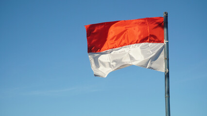 Naklejka na ściany i meble Red and white flag fluttering in the wind with blue sky Background