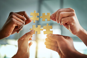 Teamwork, unity, collaboration by a group of business people completing a puzzle together,...
