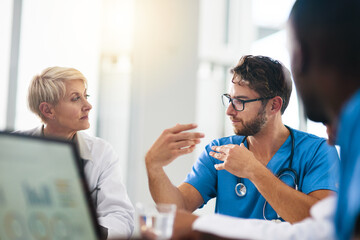Fototapeta premium Doctor, healthcare professional and medical worker in a boardroom meeting with colleagues and coworkers in the hospital. Male practitioner talking, discussing and planning a treatment with his team