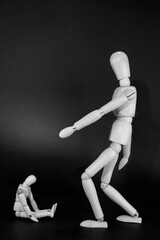 wooden mannequin scolding another smaller mannequin. black background