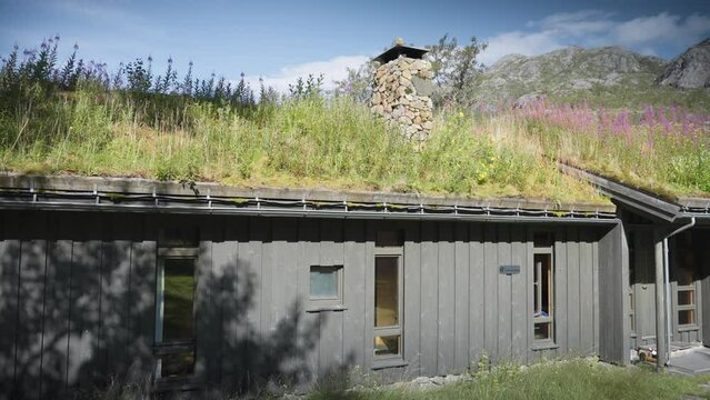 A close-up shot of the traditional sod roof house with a stone chimney. Slow-motion, pan right.