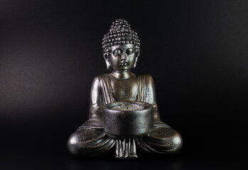 buddha statue with lit candle. black background