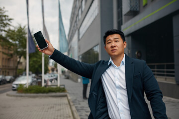 Male Businessman Catch Free Taxi at Busy Time. Asian Man Stop the Car on City Street. Guy Standing on the Road Waving his Hand Outside 