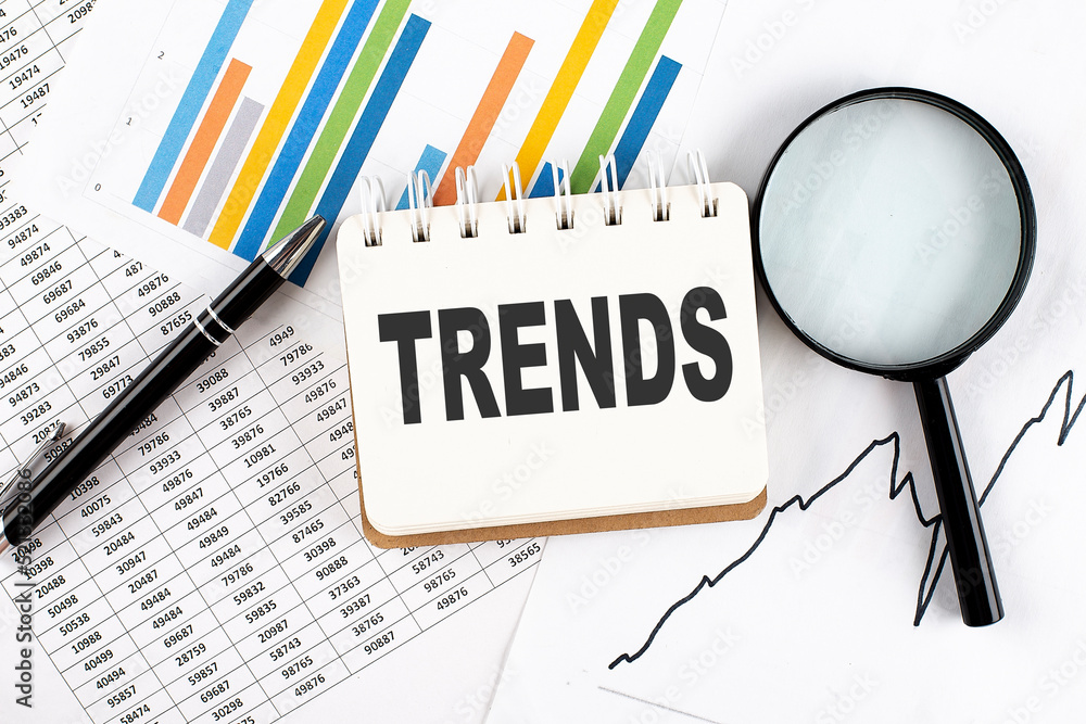 Poster trends text on notebook on the graph background with pen and magnifier