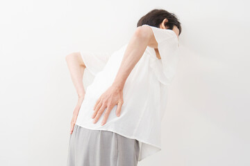 腰痛のシニア女性の後ろ姿　白バック - obrazy, fototapety, plakaty