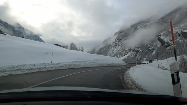 Car trip to Zermatt in winter in bad weather. The road is snow-free but the landscape is covered with snow.