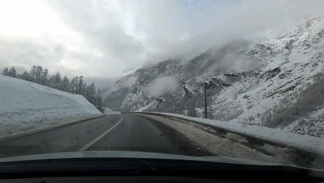 Car trip to Zermatt in winter in bad weather. The road is clear of snow but the landscape is covered with snow.