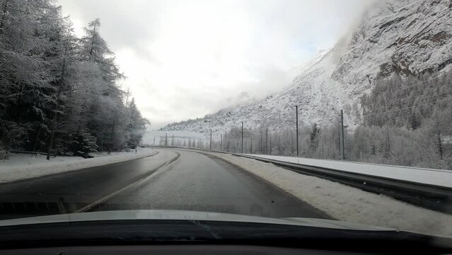 Car journey to Zermatt in winter in bad weather. The road is snow-free but the landscape is covered with snow.