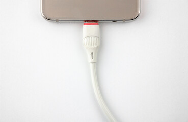Smartphone charging. Battery charging cable and smartphone on a white isolated background.