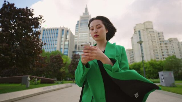 chinese woman in business suit is walking in downtown in summer day, businesswoman with smartphone