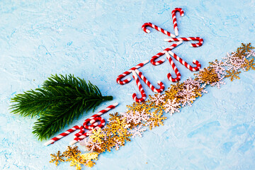 a deer and a sleigh with a fir branch decorated with Christmas caramel sticks on snowflakes on a blue background