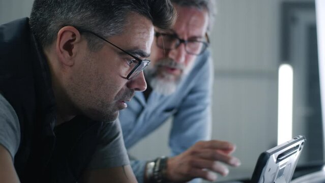 Man car service worker discussing car issues with a client during diagnostics and showing data about repairing on a digital tablet computer
