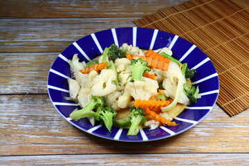 Traditional fried mixed fresh vegetable with oyster sauce serving on the plate. Famous salad menu in Asian restaurant. High fiber and low fat food menu.