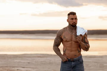 Handsome young muscular italian man posing shirtless on the beach, sunset summer time © 3kstudiok