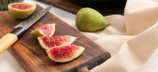 Cutting board with fresh green figs and knife on table, closeup
