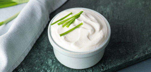 Bowl of tasty sour cream on table, closeup