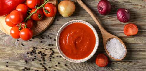 Bowl of organic tomato sauce on wooden background
