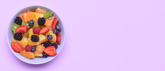 Plate of tasty fruit salad on lilac background with space for text