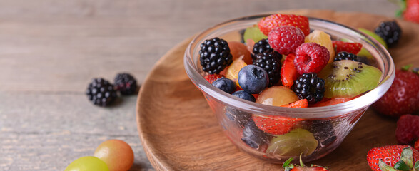 Bowl of tasty fruit salad on table, closeup