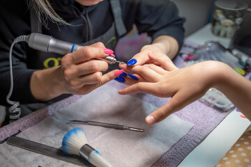 the procedure of a hardware manicure for a girl in a close-up in a beauty salon