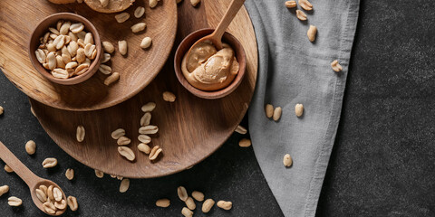Tasty peanut butter and nuts on dark background