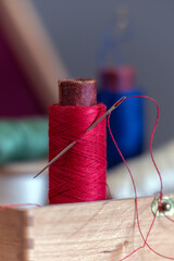 Needle with thread and spool of thread. Soft background.
