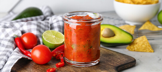 Jar of tasty salsa sauce on table