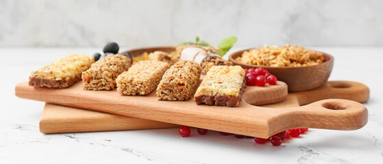 Boards with healthy cereal bars and berries on light background