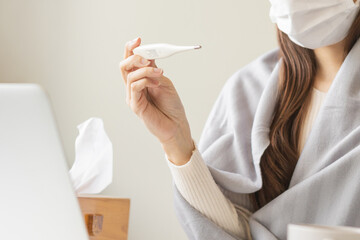 Sick, influenza asian young woman, girl hand use, holding thermometer check measure body temperature, have a fever, flu feel illness sitting work at home, office. Health care, infection of covid-19.