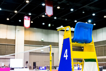 Blue chair of badminton referee with yellow colors near badminton net with blurred background in...