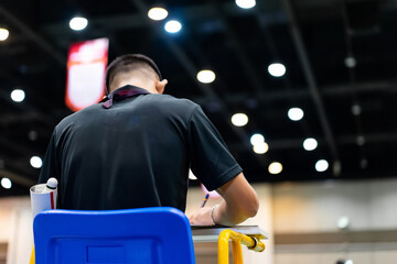 Blue chair of badminton referee with yellow colors near badminton net with blurred background in sport indoor stadium.