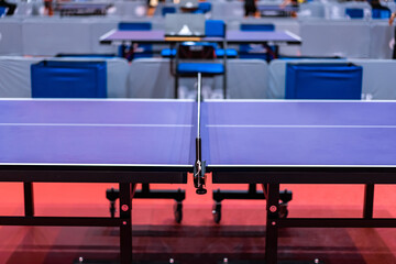 Blue table tennis or pingpong table is settle on a red, orange floor of the indoor court stadium...