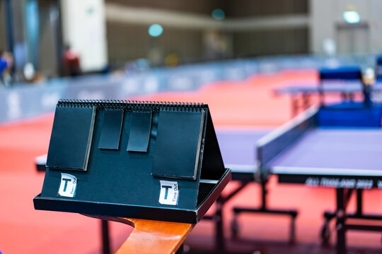 A tennis table black scoreboard is placed next to the table tennis table for referee count the score, which acts as a blurred background of pingpong tournament.