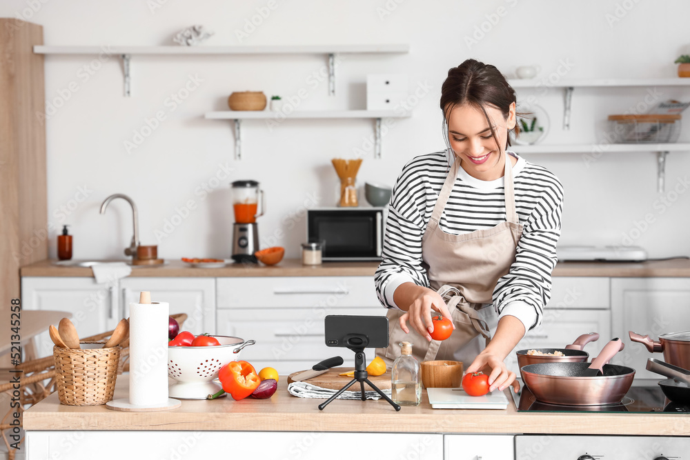 Sticker young woman with fresh tomatoes following cooking video tutorial in kitchen