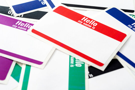 Full frame on pile of colorful blank "hello my name is" adhesive paper ID tags with copy space concept for corporate meet and greet event, conversation starter and empty identity badge