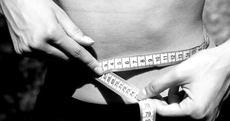 girl measuring her waist with black and white toned