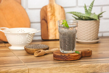 Glass of water, scoop and bowl with chia seeds on counter in kitchen