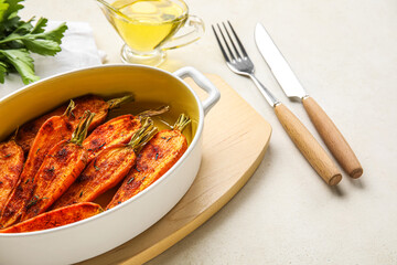 Baking dish with tasty baked carrots on light background