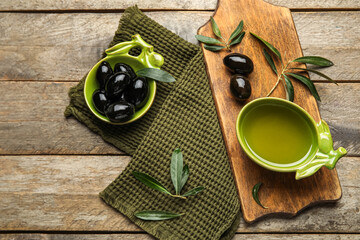 Composition with bowls of oil and olives on wooden background