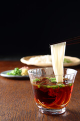 薬味を入れた麺つゆから箸上げしている素麺