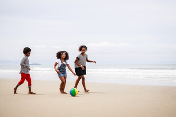 Group of African American kids play ball and have fun on a tropical beach