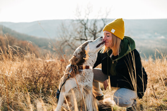 Young woman and her husky dog trek down a forest trail offering a scenic view of the trees changing colors. Fit girl takes her miniature pinscher for a walk in woods