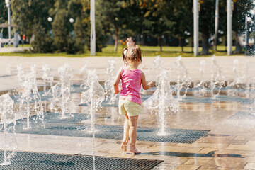 little girl playing with small fountains on the urban plaza