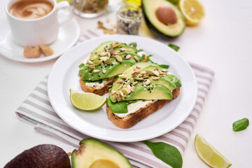Freshly made Avocado and cream cheese toasts on a white ceramic plate and ingredients